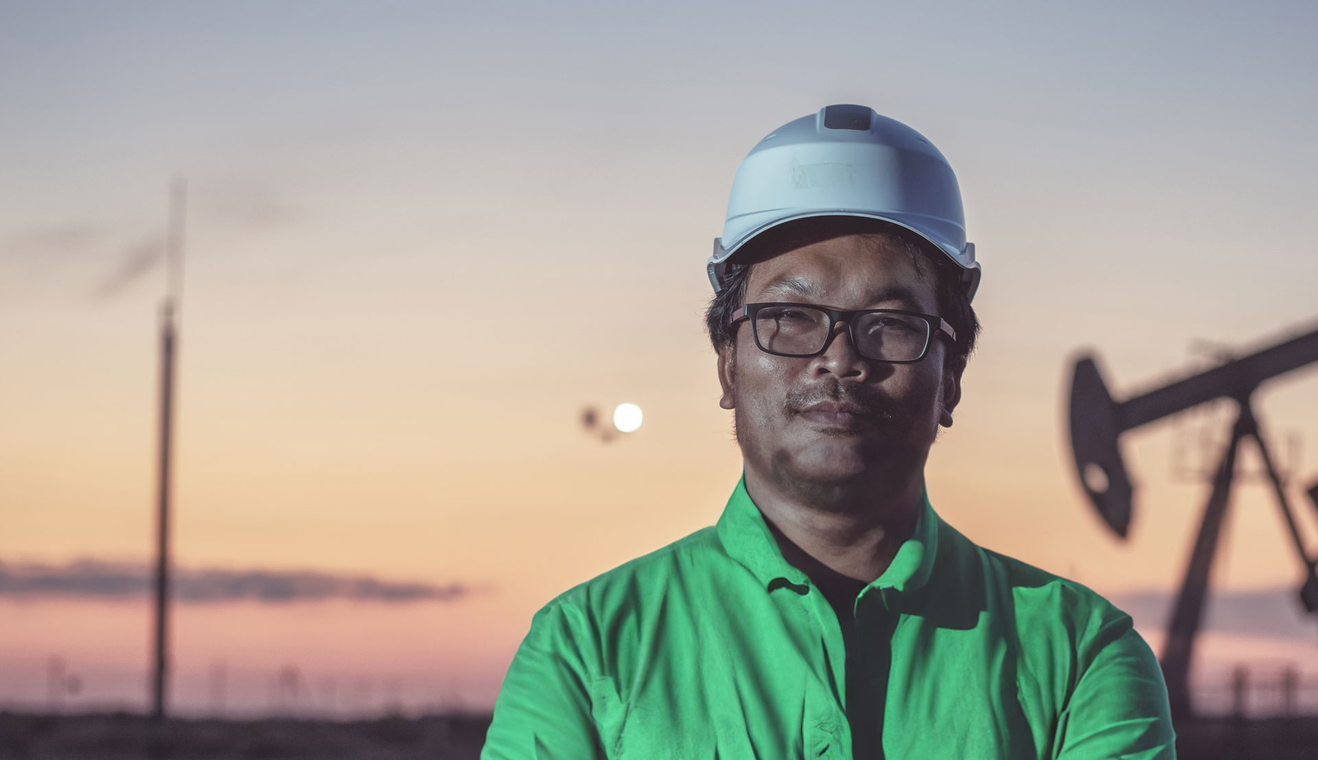 a smiling man looking straight ahead wearing glasses and a helmet, over a blurred background